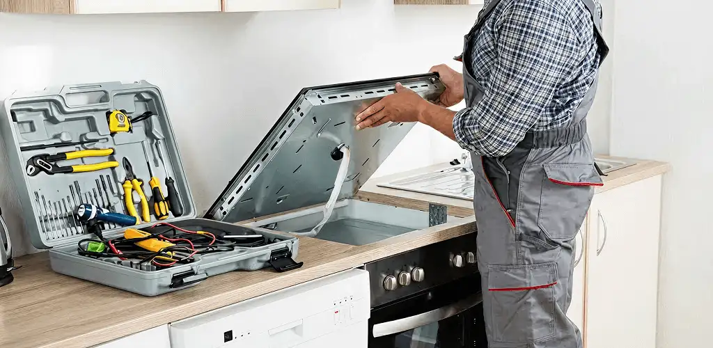 Handyman repairing a cooktop and checking wiring connections in Bloomington, IN