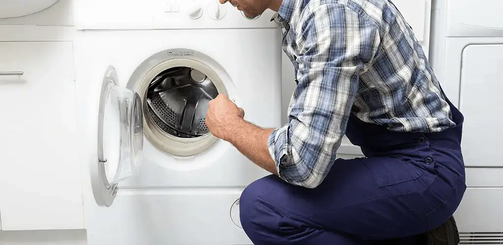 Handyman inspecting a dryer drum and internal parts for repair in Bloomington, IN