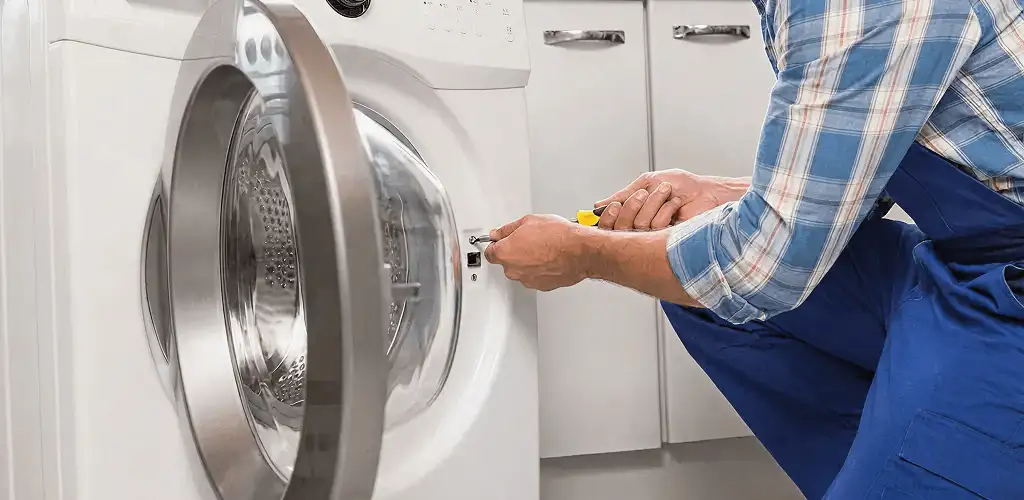 Handyman repairing a clothes dryer and checking electrical connections in Bloomington, IN