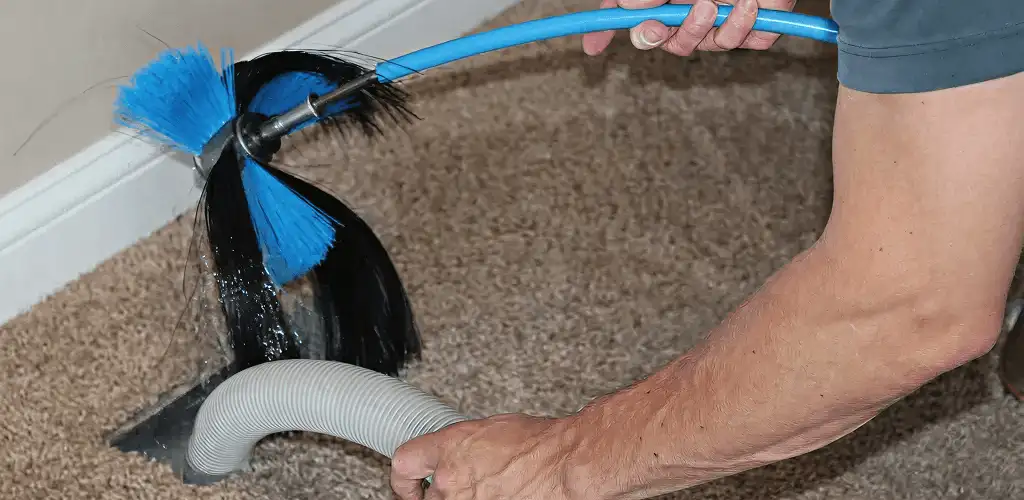 Dryer vent cleaning technician brushing lint from a vent line in Bloomington, IN