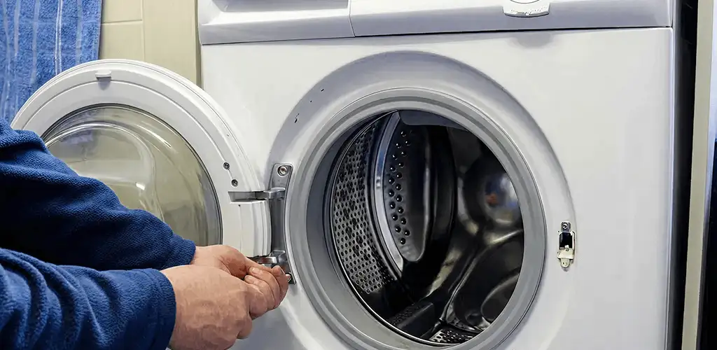 Washing machine repair handyman checking a front-load washer door and latch in Bloomington, IN