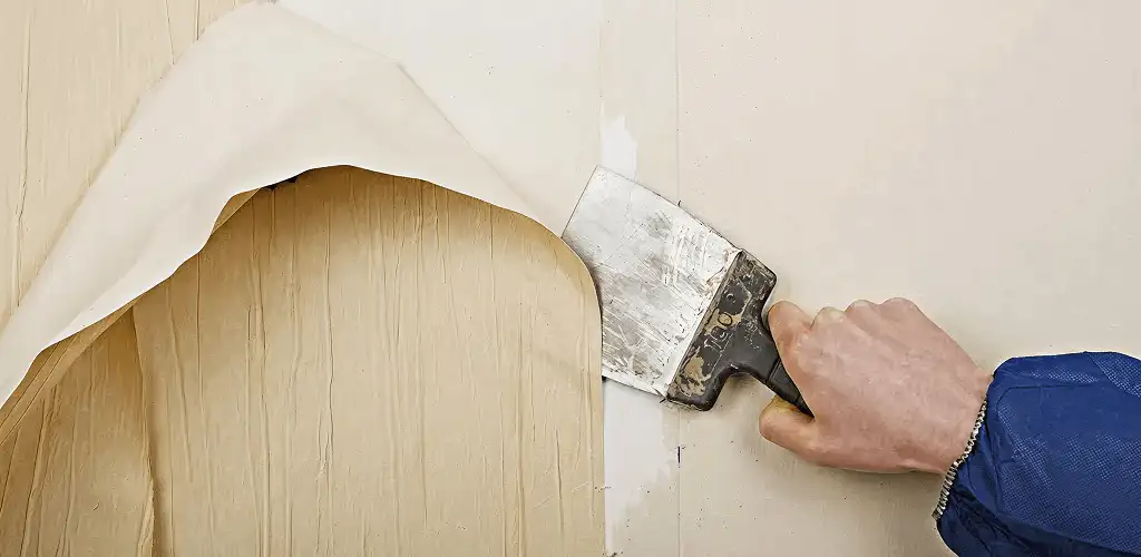 Handyman removing wallpaper with a scraper for wall preparation in Bloomington, IN