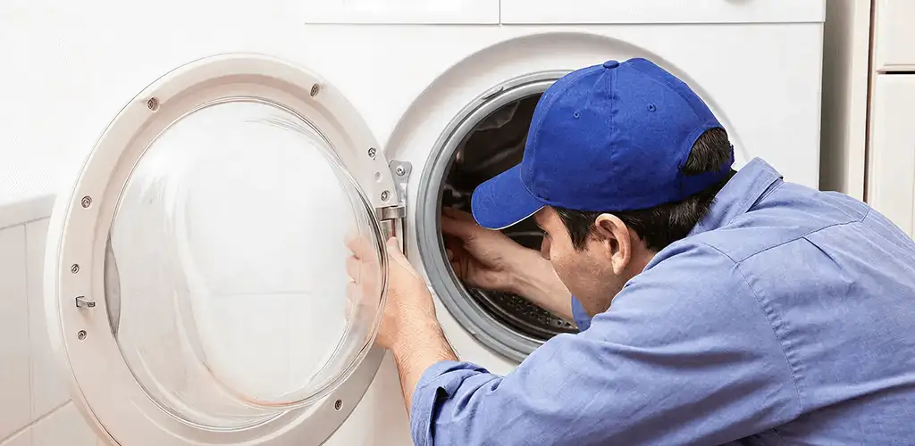 Washing machine repair handyman inspecting a front-load washer drum in Bloomington, IN