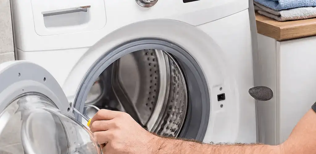 Handyman repairing a front-load washing machine and inspecting the drum in Bloomington, IN