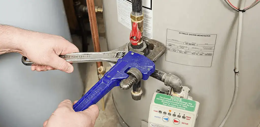 Water heater repair technician tightening the shutoff valve and supply line in Bloomington, IN